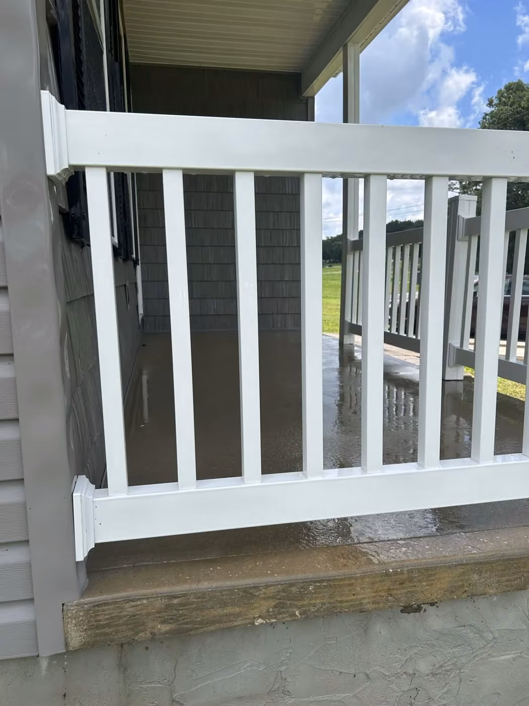 Porch railing after cleaning; the porch surface is still wet.