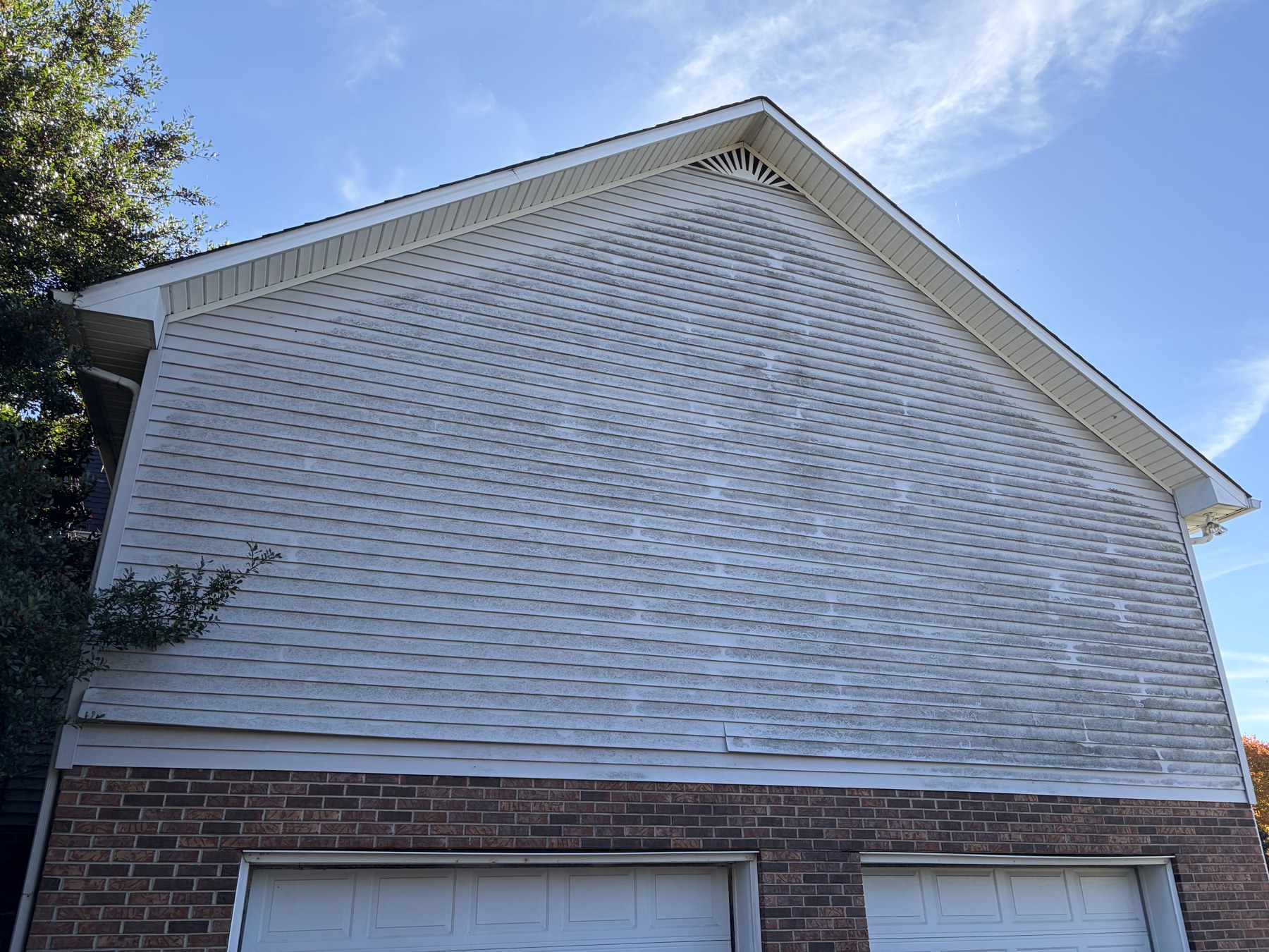 Algae-stained vinyl gable siding before soft wash in Algood, TN