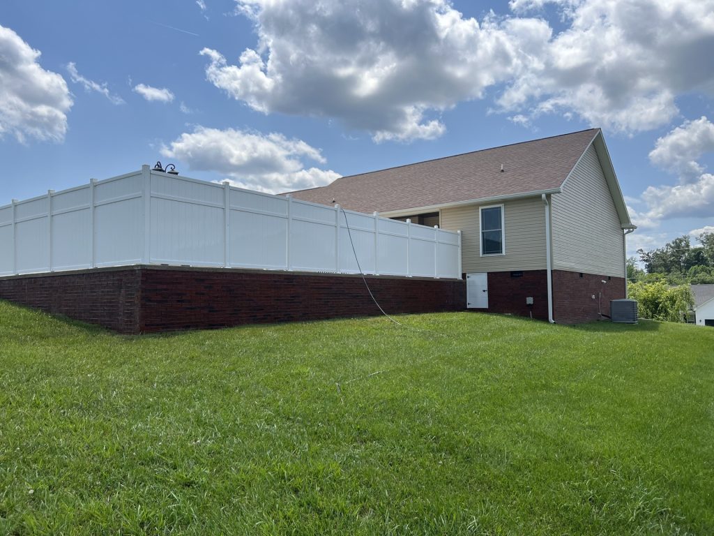 Clean siding and white vinyl fence after house washing in Cookeville, Tennessee