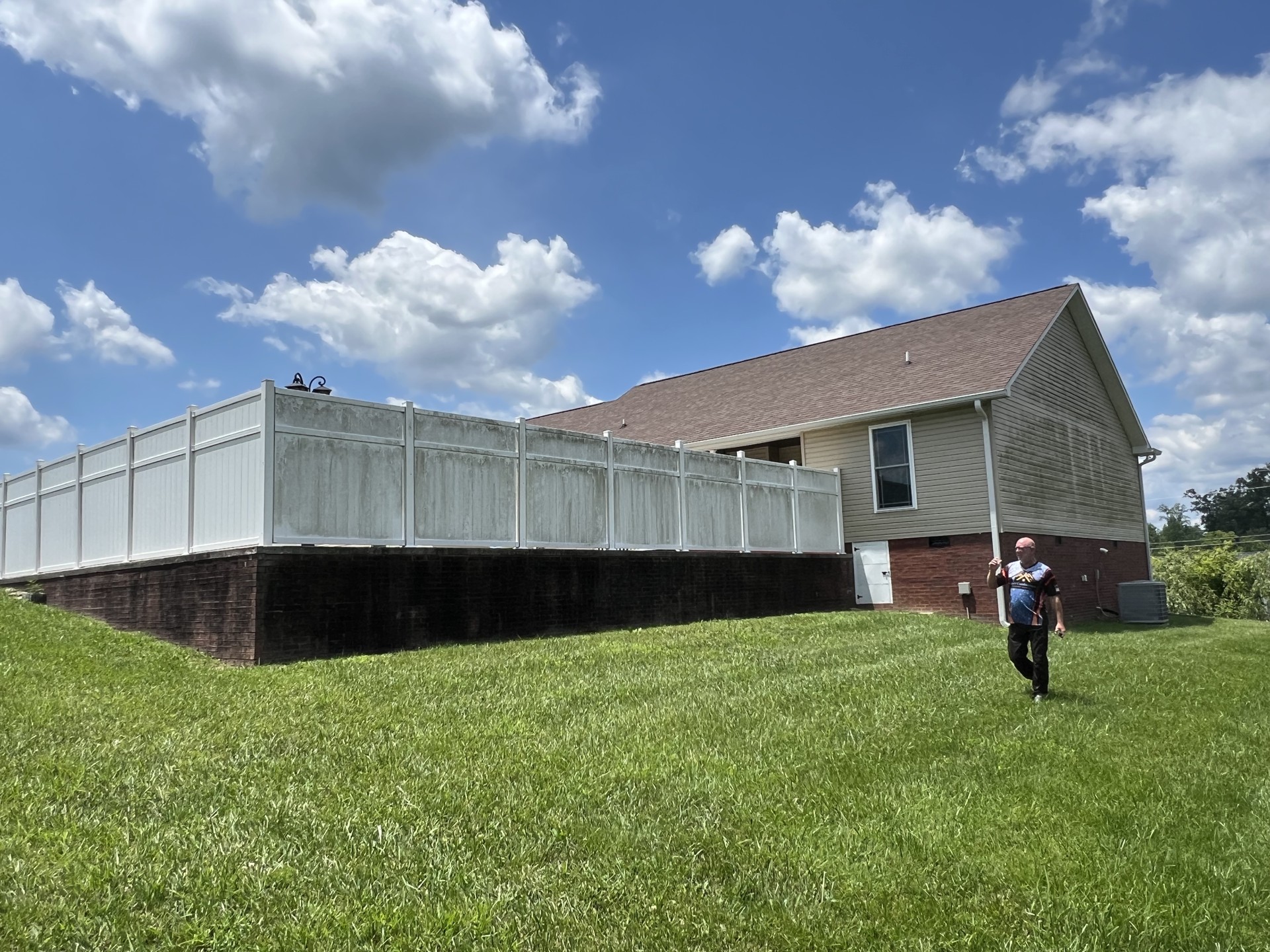 Algae-stained siding and white vinyl fence before exterior cleaning in Cookeville, TN